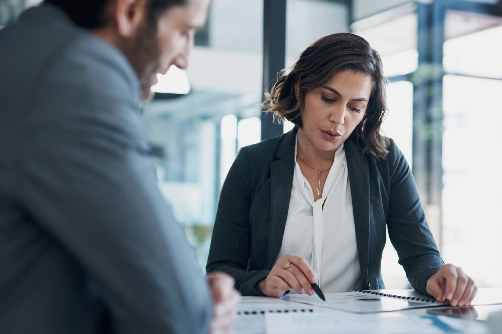 Une conseillère en gestion de patrimoine explique un document à un homme. 