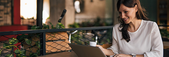 Femme assise dans un café regardant ses investissements sur un ordinateur portable