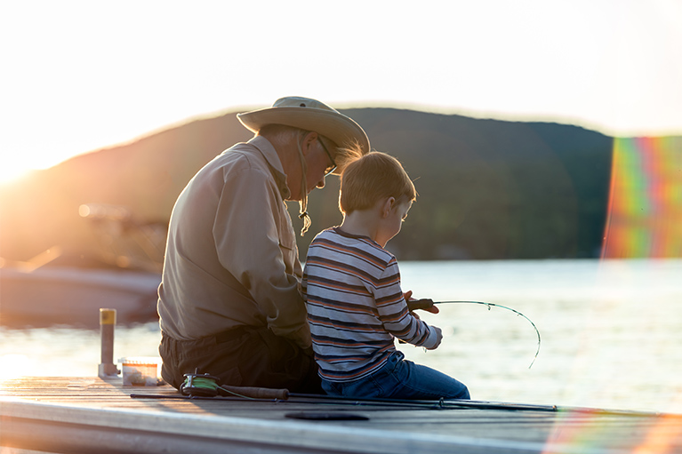 Image d’un grand-père avec son petit-fils en train de pêcher.