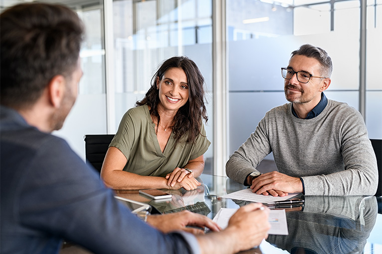 Couple d'âge mûr souriant rencontrant un directeur de banque pour investir