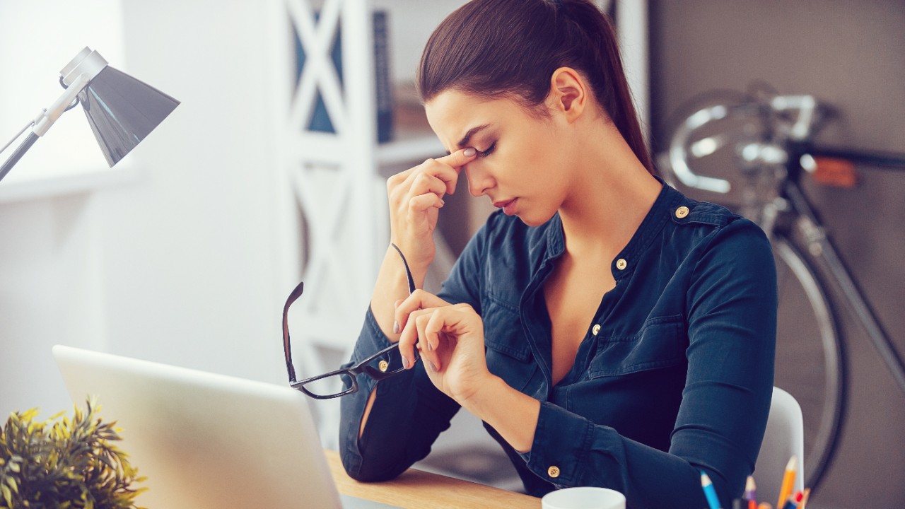 Une femme qui réfléchit assise à son bureau.