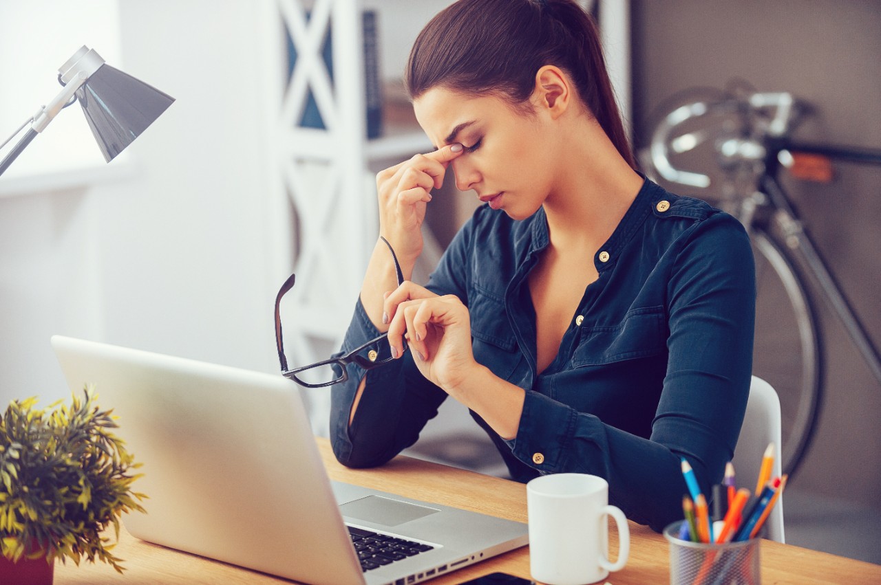 Une femme qui réfléchit assise à son bureau.