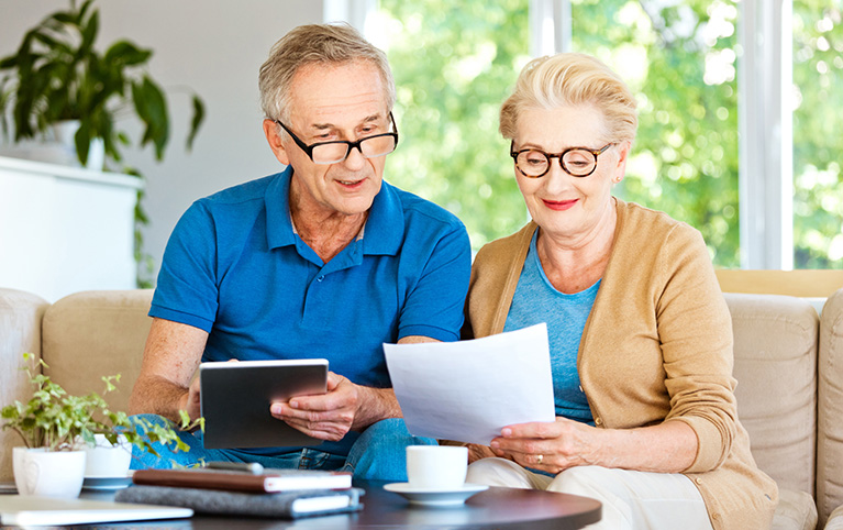 Deux personnes qui consultent une tablette électronique et un document.