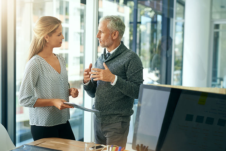 Une femme et un homme qui parlent dans un bureau.