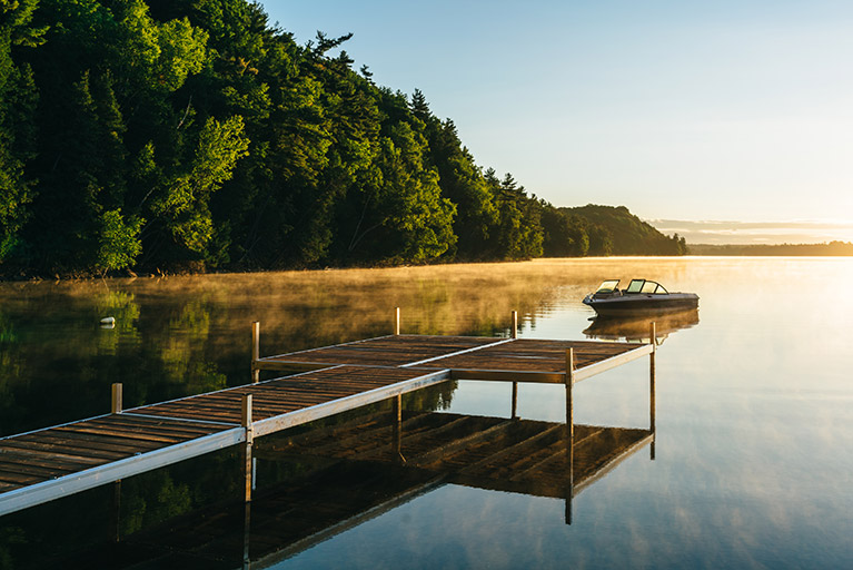 Photo d'un quai sur un lac au soleil levant.