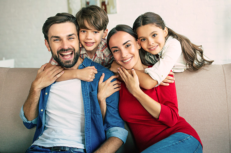 Jeune famille assise sur un canapé.