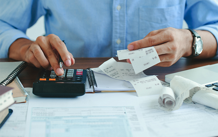 Main d'un homme travaillant sur une calculatrice. 