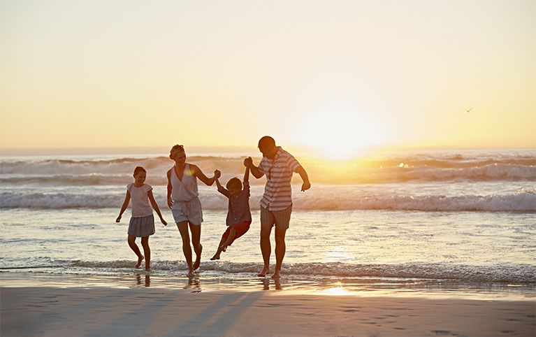 Famille sur la plage au couché du soleil.