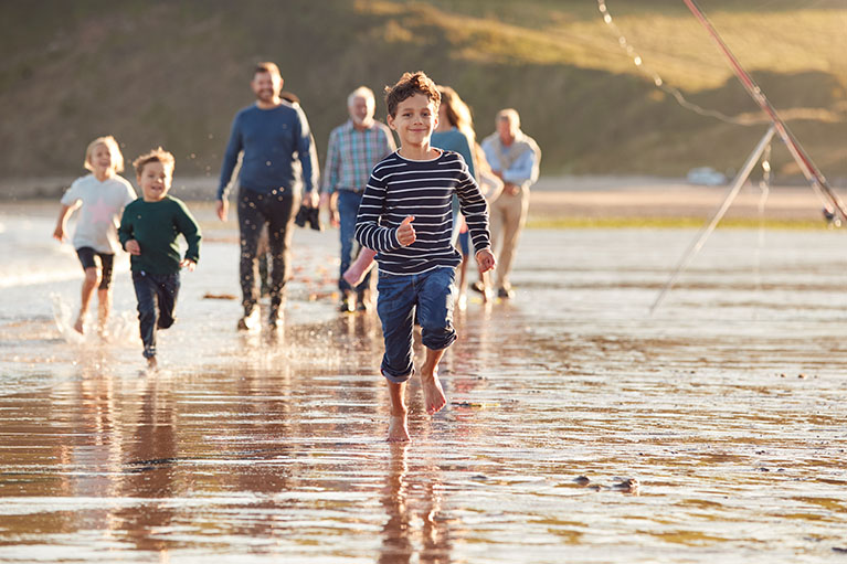 Des enfants cours dans l'eau; des adultes marchent dans l'eau en arrière d'eux.