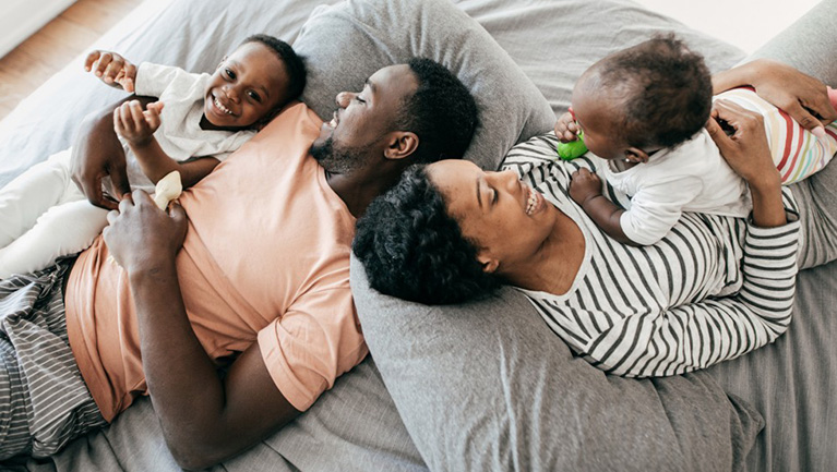 Une femme enceinte et son conjointe jouent au salon avec leur enfant.