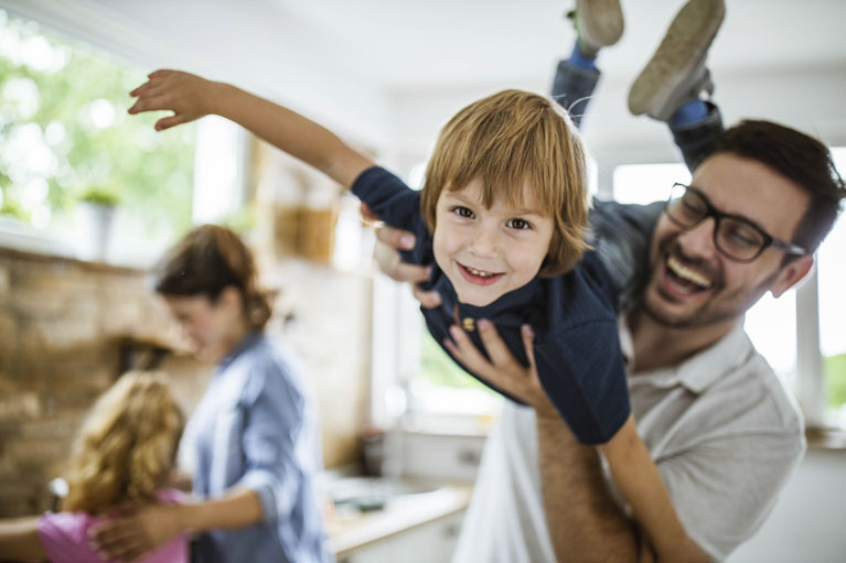 Un homme qui s'amuse avec son enfant et une femme qui discute avec sa fille.