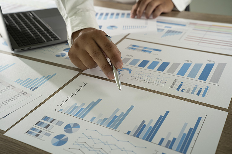 Main qui point d'un stylo des tableaux graphiques portant le sujet d'investissement.