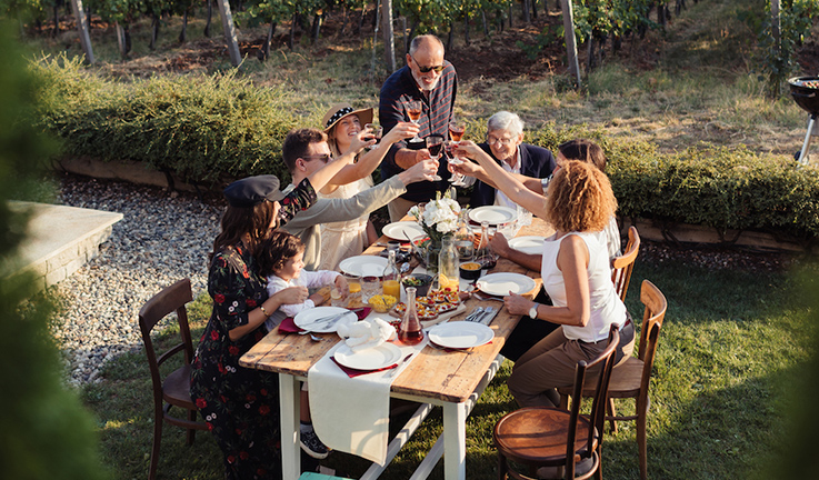 Une famille qui trinquent autour d’une table dans une cour.