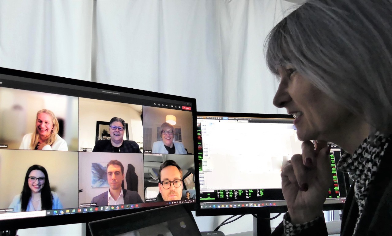 Une femme regardant une conférence sur un écran.