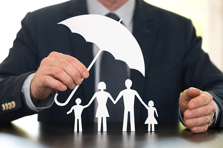 Un homme tenant un paraplui en papier devant une famille en papier.