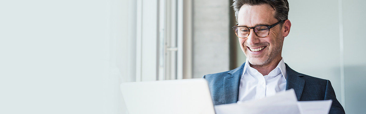 Un homme souriant qui consulte son ordinateur.