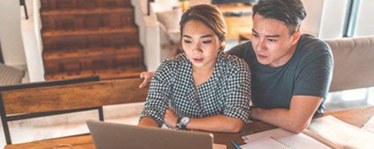 Un homme et une femme consultent leurs finances sur un ordinateur portable.