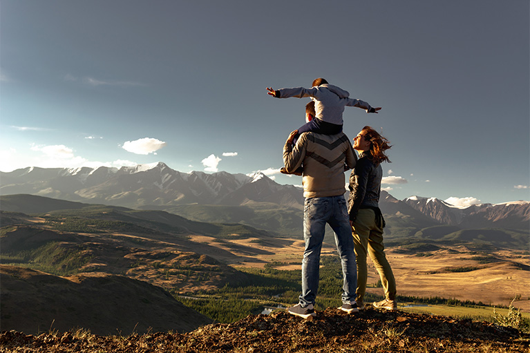 Famille d'un père, une mère et leur jeune fils qui marchent dans les montagnes.