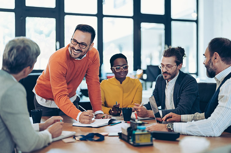 Équipe de collègues professionnels discutant agréablement lors d’une réunion d’affaires dans un environnement de bureau moderne.