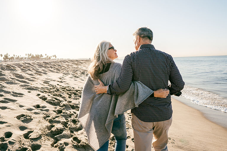 Un couple marche sur une plage.