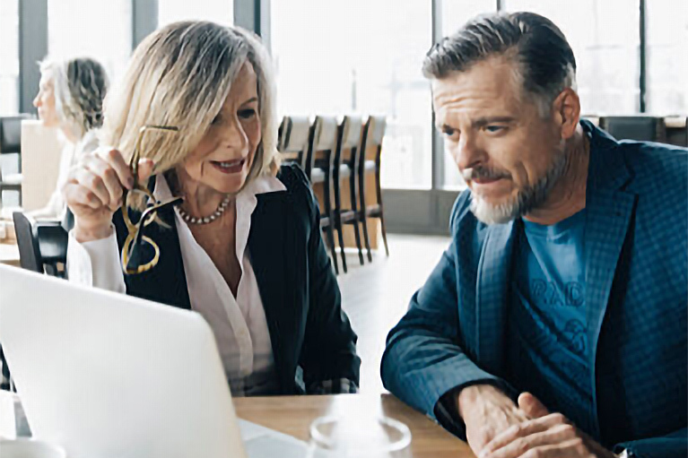 Image d’une femme et un homme au restaurant regardant l’écran d’un ordinateur. 