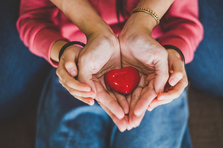 Deux mains qui tiennent un coeur pour illuster les assurances.