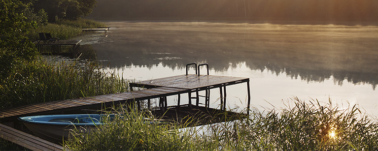 Photo d'un quai devant un lac au lever du soleil. 