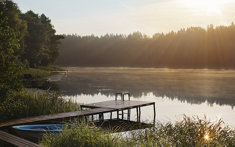 Photo d'un quai devant un lac au lever du soleil. 