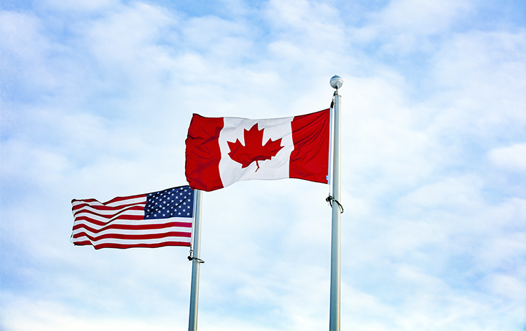 Photo deux drapeaux canadien et américain flottant au vent. 