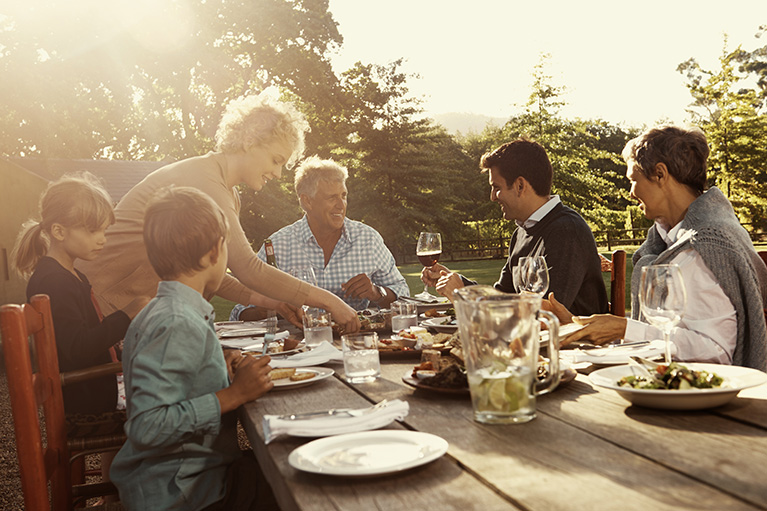 Photo d'une famille multigénérationnelle en train de déjeuner ensemble à l'extérieur