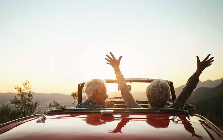 Image d'un couple âgé conduisant vers le coucher du soleil après la retraite.