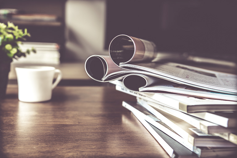 Image d'une tasse de café et magazine sur une table en bois.