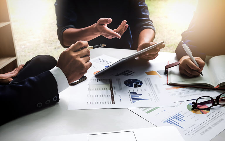 Trois personnes assises à une table examinent les documents d'investissement de leurs clients.