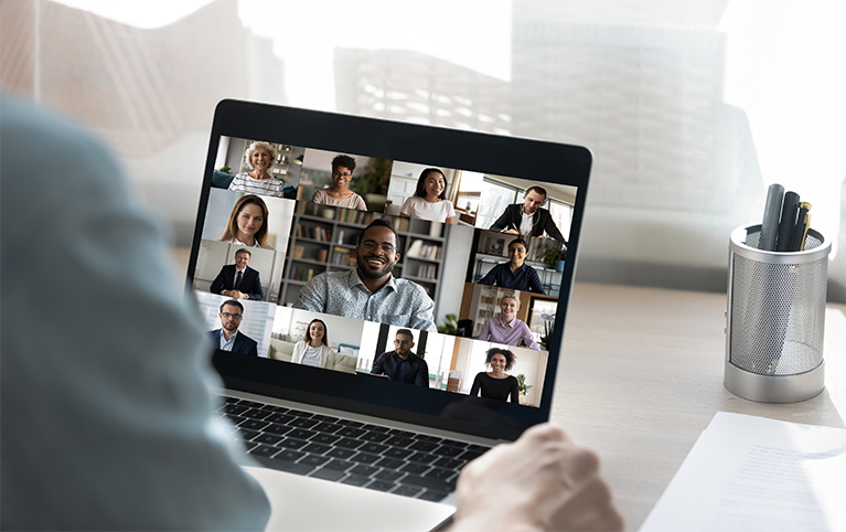 Back view of male employee have online video call on laptop with diverse multiethnic colleagues, man worker involved in webcam conference or virtual event on computer with multiracial businesspeople