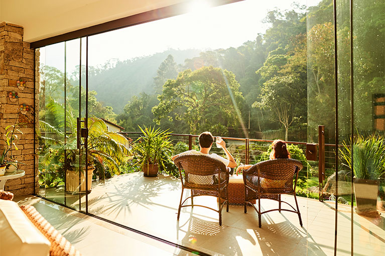 Couple assis sur une terasse au soleil devant une vue de forêt ensoleillé 