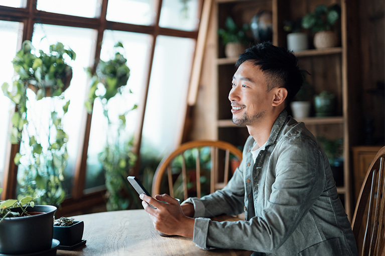 A man smiling with a mobile phone in his hands.