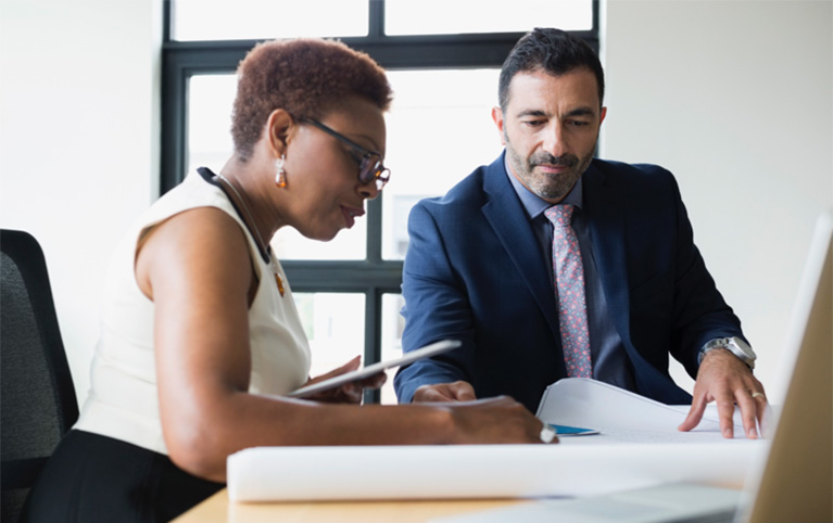 Un homme et une femme assis à un bureau travaillent.