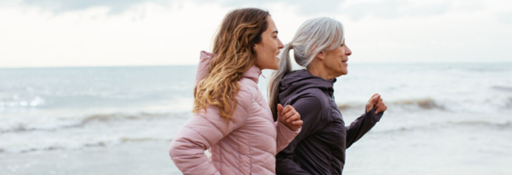 Mère et fille, de profil, courant sur une plage